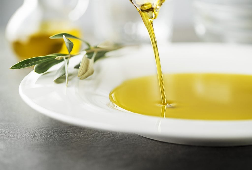 Bottle Of Healthy Virgin Olive Oil Pouring To Plate Close Up. He
